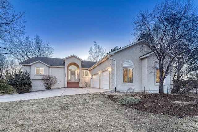 view of front facade with an attached garage, driveway, and stucco siding