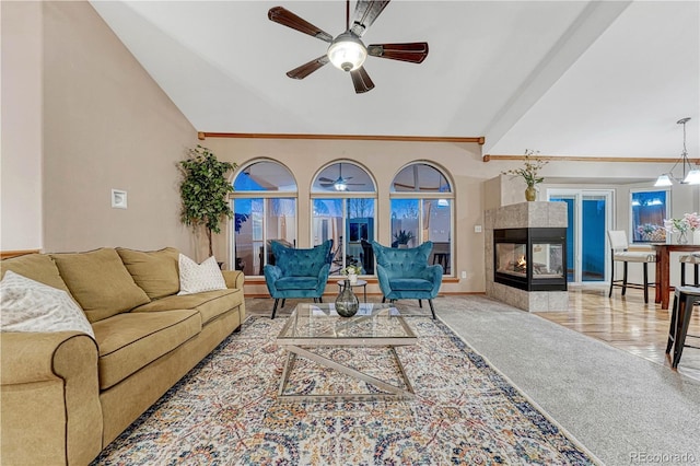 carpeted living area featuring ceiling fan, a tile fireplace, and vaulted ceiling