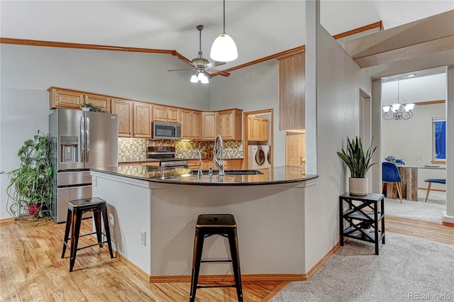 kitchen with independent washer and dryer, ceiling fan with notable chandelier, a sink, tasteful backsplash, and appliances with stainless steel finishes