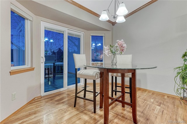 dining space featuring baseboards, wood finished floors, a chandelier, and ornamental molding