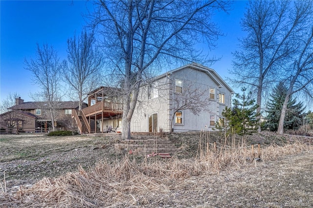 view of front of house featuring stucco siding, a wooden deck, and stairs