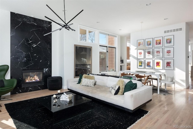 living room featuring a wall of windows, a fireplace, a chandelier, and light wood-type flooring