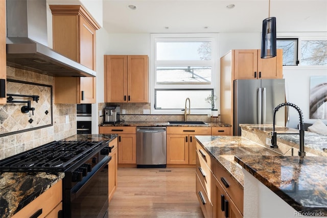 kitchen featuring appliances with stainless steel finishes, tasteful backsplash, sink, dark stone countertops, and wall chimney exhaust hood