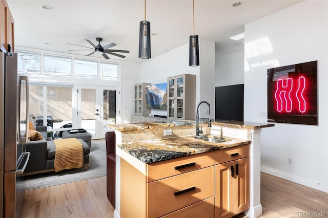 kitchen with dark stone countertops, sink, a wealth of natural light, and stainless steel refrigerator