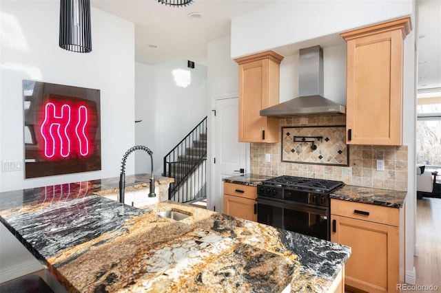 kitchen with wall chimney exhaust hood, sink, tasteful backsplash, dark stone counters, and black gas range