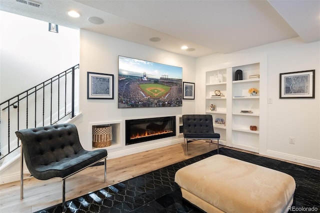 living area with hardwood / wood-style floors and built in shelves