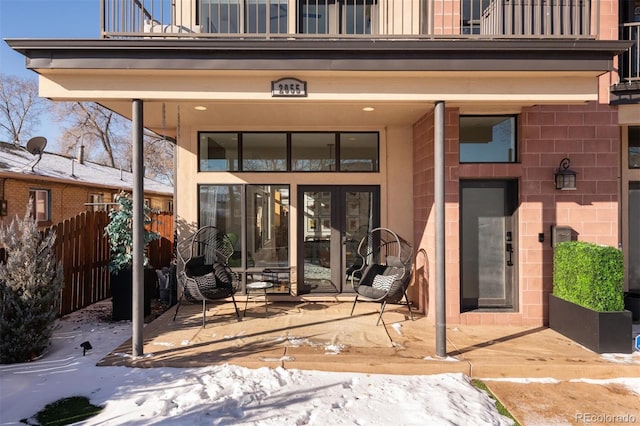 snow covered back of property featuring a patio area and a balcony