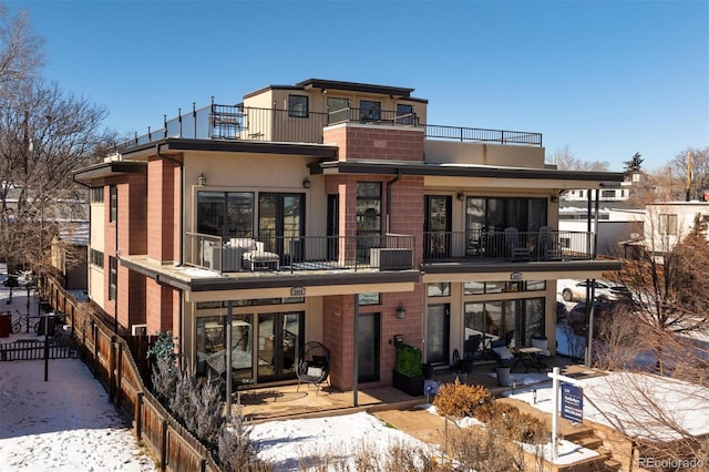 snow covered back of property featuring a balcony