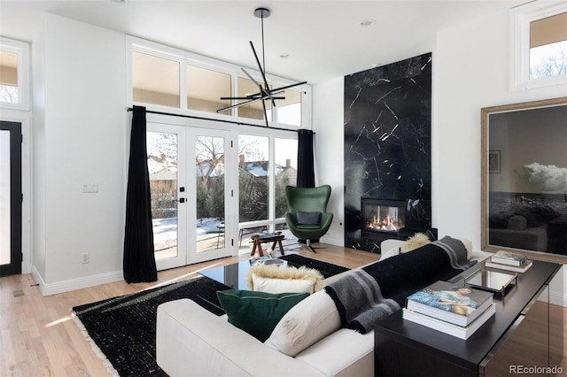 living room with french doors, a fireplace, and light hardwood / wood-style flooring