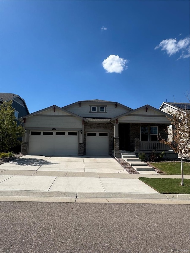 view of front of home with concrete driveway, an attached garage, a porch, and stone siding