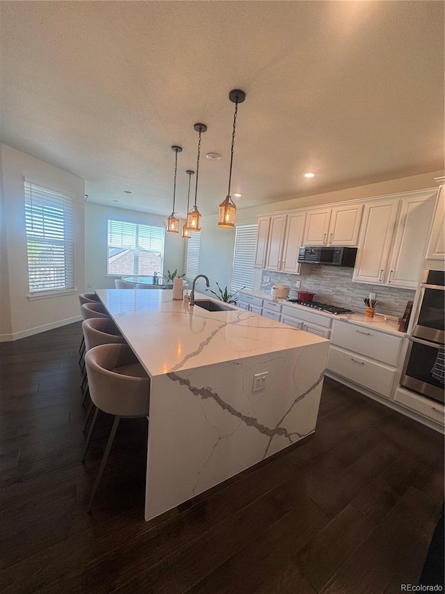 kitchen with gas cooktop, dark wood-style flooring, ventilation hood, decorative backsplash, and white cabinetry