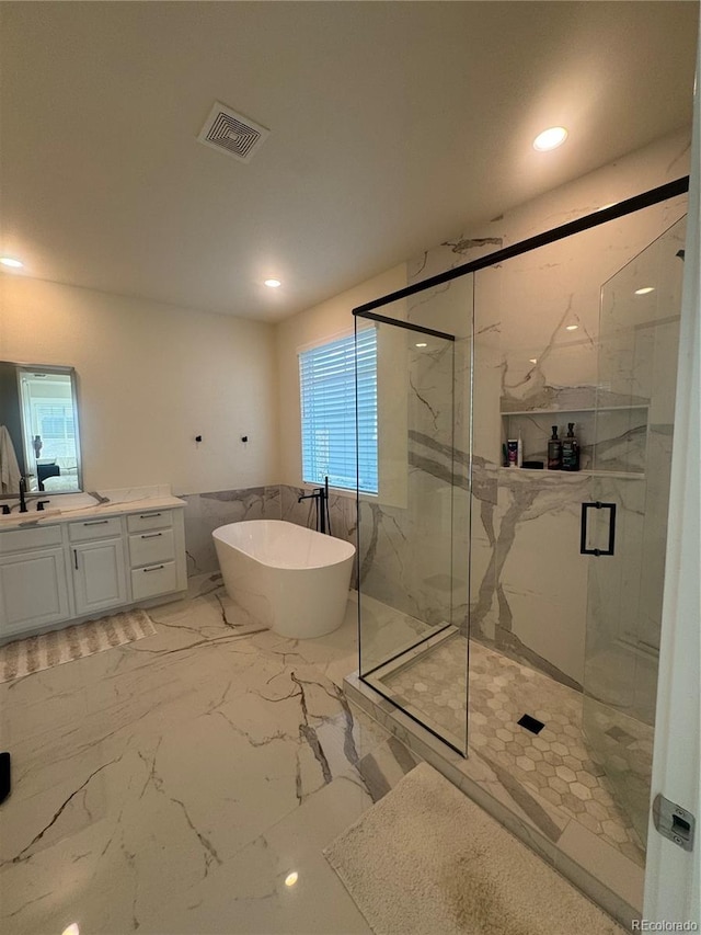 bathroom featuring a freestanding bath, a marble finish shower, vanity, marble finish flooring, and recessed lighting