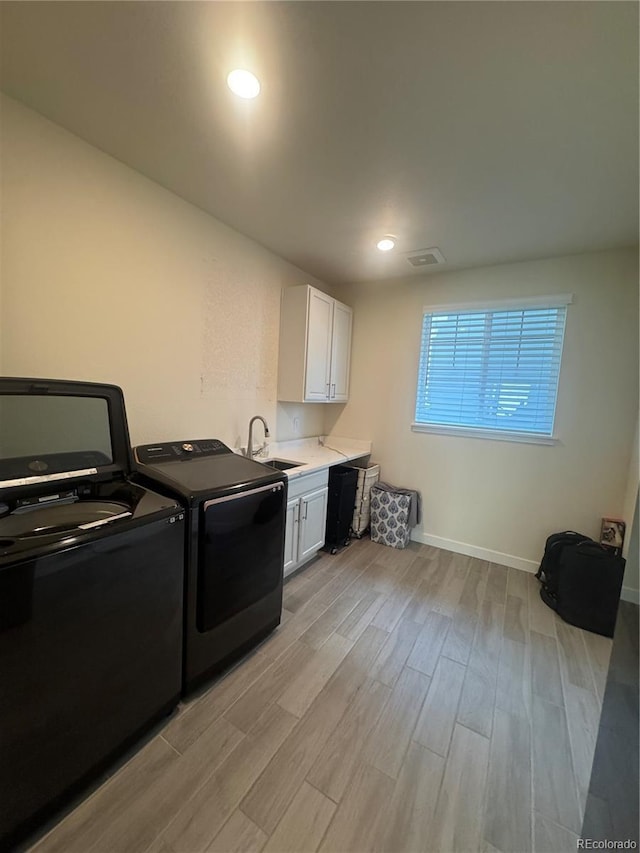 laundry room with cabinet space, washing machine and clothes dryer, light wood-style flooring, baseboards, and recessed lighting