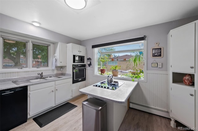 2633 Summit Dr, Colorado Springs, CO 80909 - kitchen with black appliances, baseboard heating, light countertops, wainscoting, and light wood-style floors