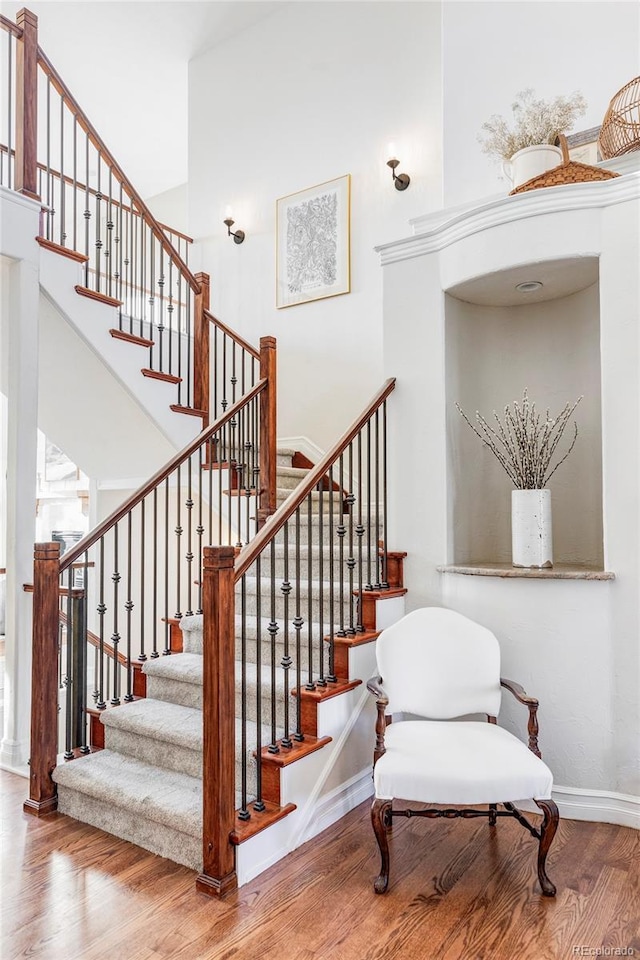 stairway featuring a towering ceiling and wood-type flooring