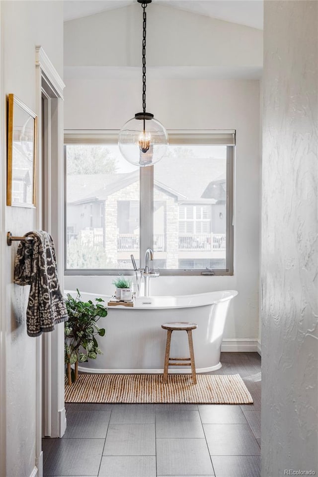 bathroom with tile patterned flooring, a bathtub, and lofted ceiling