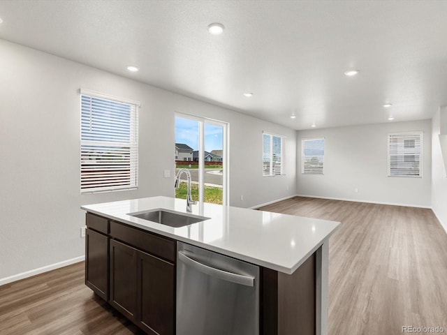 4635 Goldflower Dr, Johnstown, CO 80534 - kitchen featuring stainless steel dishwasher, light countertops, light wood-style flooring, dark brown cabinets, and a kitchen island with sink