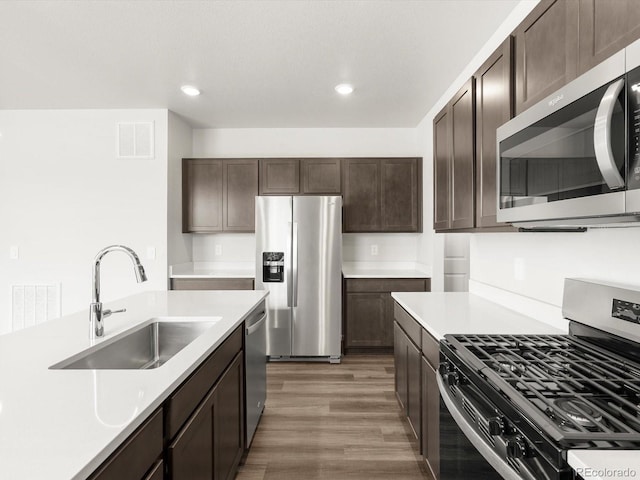 4635 Goldflower Dr, Johnstown, CO 80534 - kitchen with appliances with stainless steel finishes, dark brown cabinets, light countertops, light wood-style flooring, and recessed lighting
