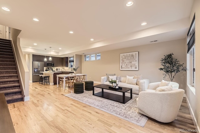 2442 S Bannock St, Denver, CO 80223 - living area featuring stairway, light wood finished floors, recessed lighting, baseboards, and a tray ceiling