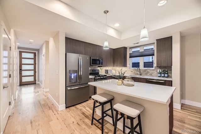 2442 S Bannock St, Denver, CO 80223 - kitchen with appliances with stainless steel finishes, dark brown cabinets, a kitchen breakfast bar, backsplash, and light countertops