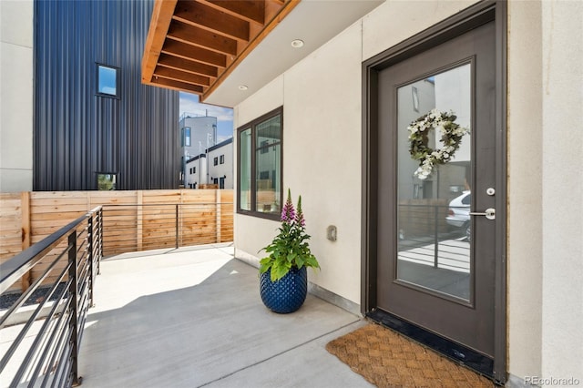 doorway to property featuring fence and stucco siding