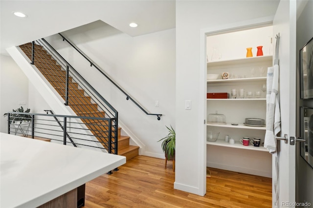 stairway with wood finished floors, recessed lighting, and baseboards
