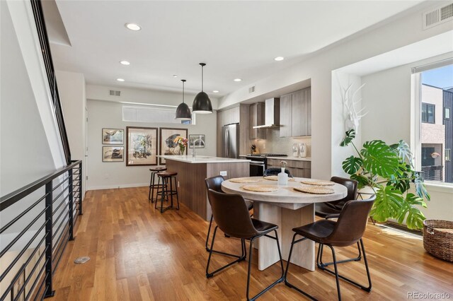 dining room featuring light wood-type flooring, recessed lighting, and baseboards