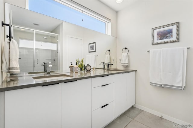 bathroom with baseboards, double vanity, a stall shower, and tile patterned floors