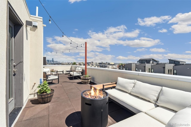 view of patio / terrace with an outdoor living space with a fire pit, a city view, and a balcony