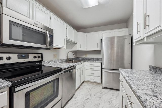 kitchen with light stone counters, stainless steel appliances, sink, and white cabinets