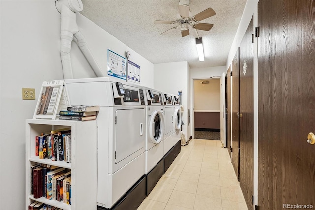 clothes washing area with ceiling fan, light tile patterned flooring, washing machine and clothes dryer, and a textured ceiling