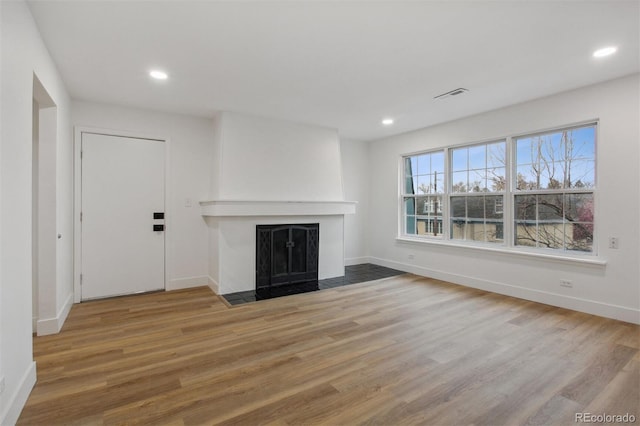 9120 E Girard Ave Unit 12, Denver, CO 80231 - unfurnished living room featuring a fireplace with flush hearth, wood finished floors, and recessed lighting