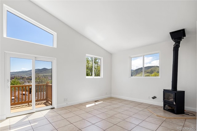 420 Sunshine Pkwy, Golden, CO 80403 - unfurnished living room featuring a wood stove, light tile patterned floors, high vaulted ceiling, baseboards, and a mountain view