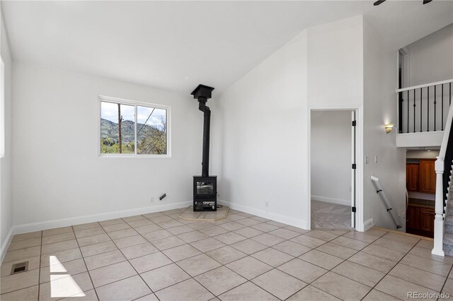 420 Sunshine Pkwy, Golden, CO 80403 - unfurnished living room with a wood stove, light tile patterned flooring, lofted ceiling, and baseboards