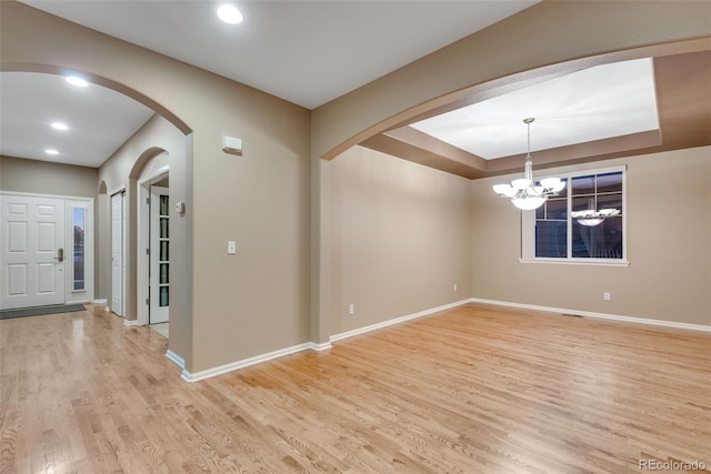 interior space featuring a raised ceiling, light hardwood / wood-style flooring, and a chandelier