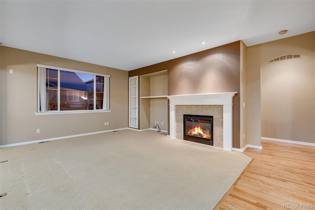 unfurnished living room featuring hardwood / wood-style flooring and a tile fireplace