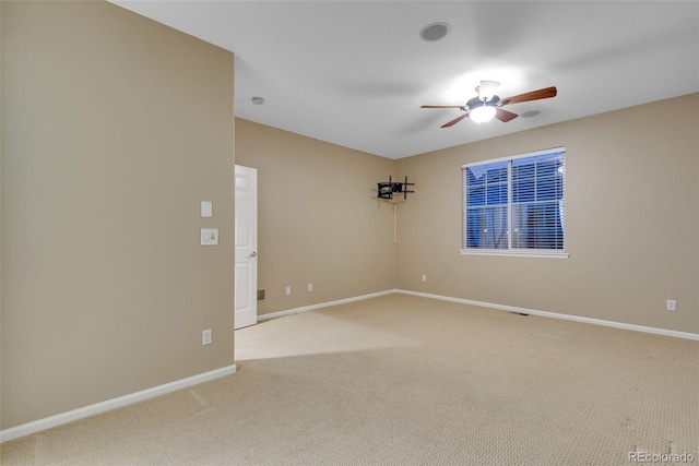 spare room with ceiling fan and light colored carpet