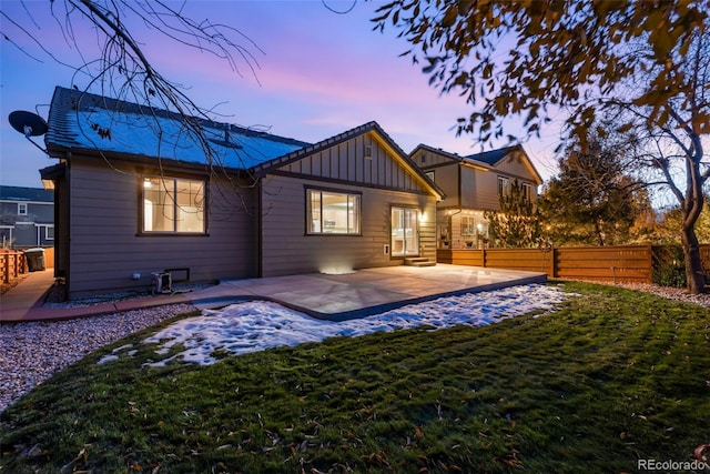 back house at dusk with a yard and a patio