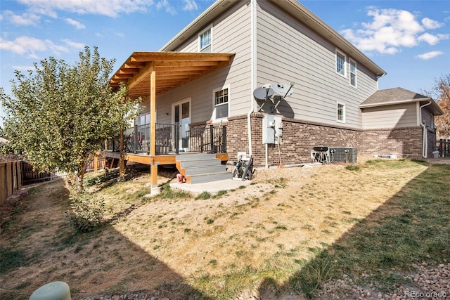 back of property featuring central AC unit, fence, and brick siding