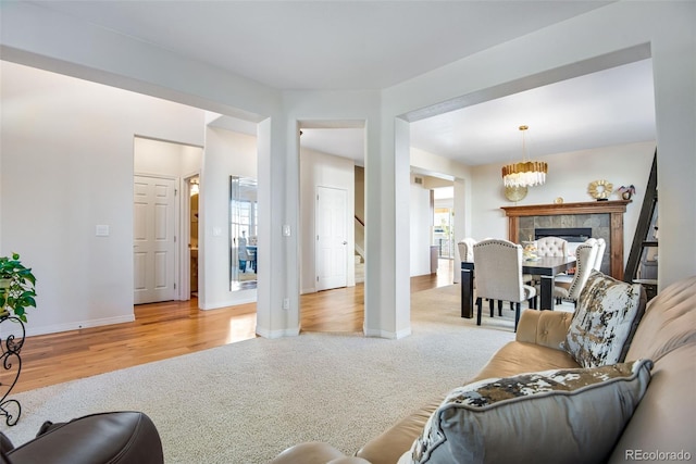 living room featuring carpet floors, an inviting chandelier, wood finished floors, and baseboards