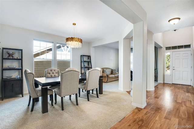 dining area with a chandelier, light colored carpet, light wood-style floors, and baseboards