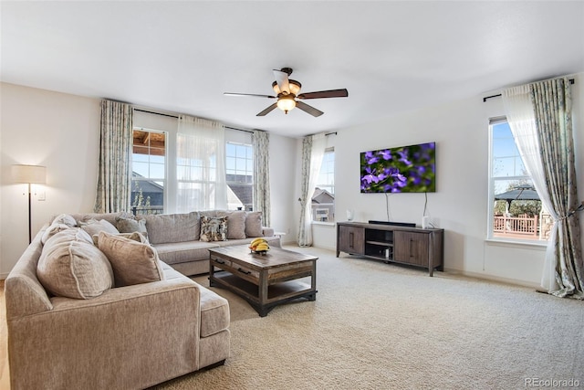 living room with a healthy amount of sunlight, ceiling fan, baseboards, and light colored carpet