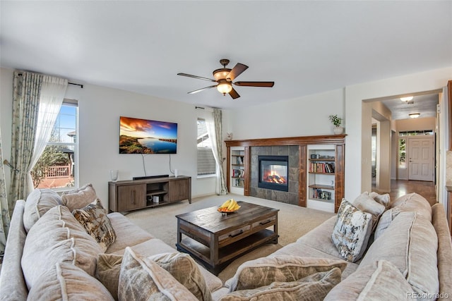 living room featuring carpet, ceiling fan, and a tile fireplace