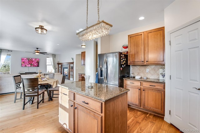 kitchen with plenty of natural light, stainless steel fridge, open floor plan, and light wood-style flooring