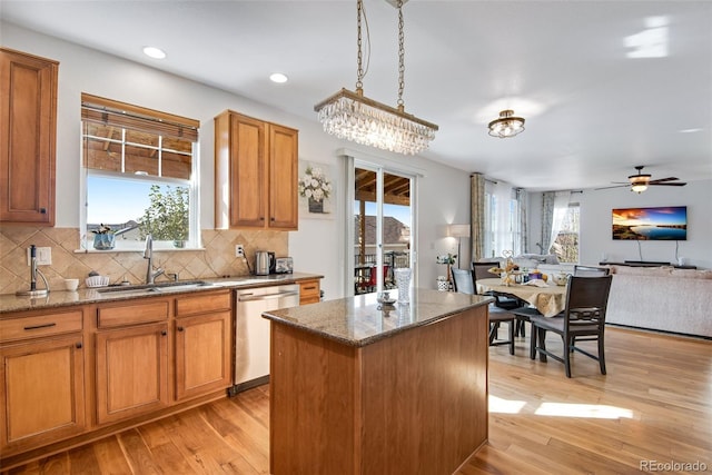 kitchen featuring a sink, light wood-style floors, open floor plan, stainless steel dishwasher, and a center island