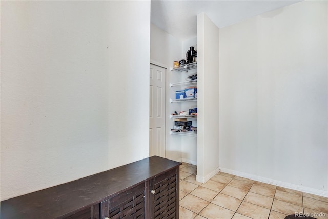 hallway with light tile patterned floors and baseboards