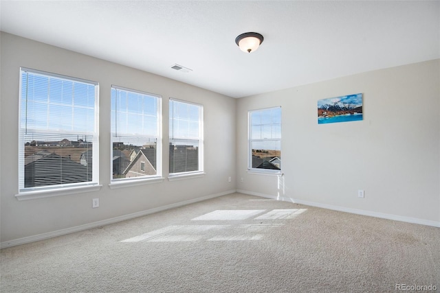 spare room featuring baseboards, visible vents, and light colored carpet