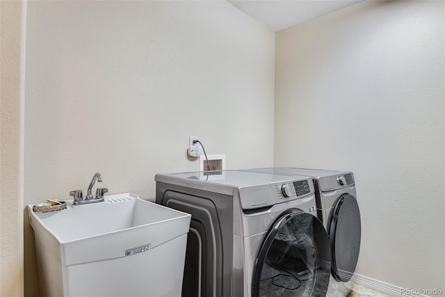 laundry area featuring independent washer and dryer, laundry area, a sink, and baseboards