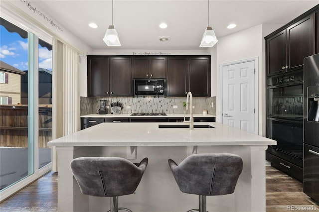 25127 E Maple Ave, Aurora, CO 80018 - kitchen with black appliances, a sink, dark wood-style flooring, tasteful backsplash, and a kitchen bar