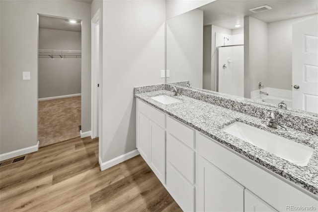 bathroom with dual vanity, independent shower and bath, and hardwood / wood-style flooring